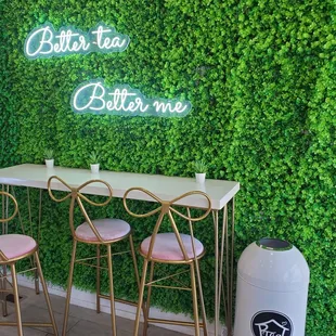 a table and chairs in front of a green wall