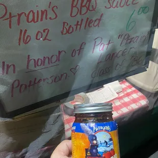 a hand holding a jar of bbq sauce