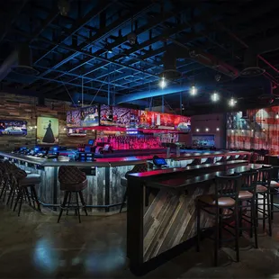 a bar with stools and neon lights