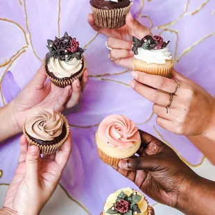 a group of people holding cupcakes