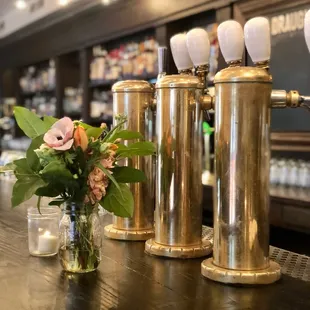 a row of brass beer taps on a bar