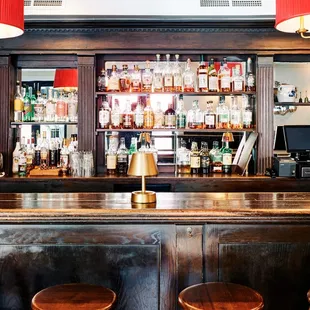 a bar with stools and bottles of alcohol