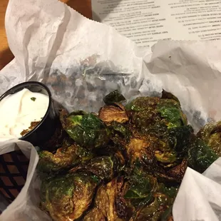 a basket of brussels sprouts with a side of sour cream