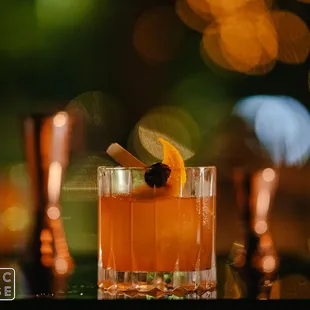 a drink in a glass with an orange garnish