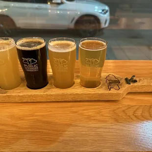 a wooden serving tray with four different beers