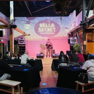 people sitting at tables in front of a stage