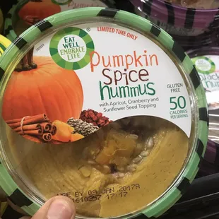 a person holding a container of pumpkin spice hummuss