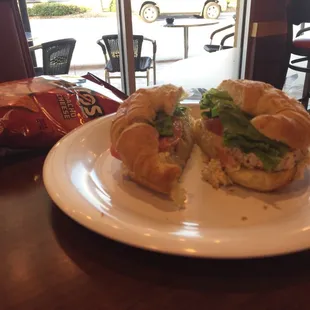 Chicken salad sandwich on a croissant with chips.