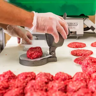 a man in a kitchen making hamburger patties
