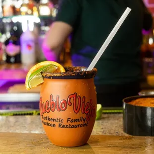 a drink with a straw and a lime garnish