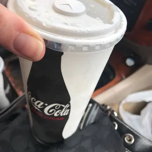 a hand holding a cup of coca cola