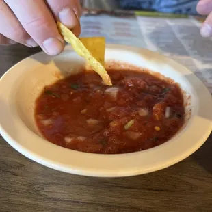 a person dipping a tortilla into a bowl