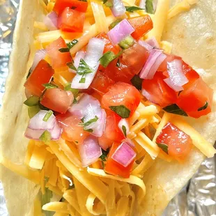 a taco with cheese, tomatoes, and onions