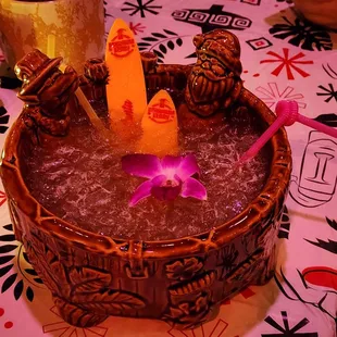 a drink in a wooden bowl with a purple flower