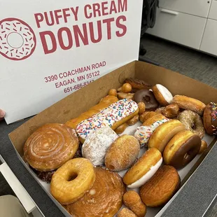 A variety of different doughnuts with the added touch of a couple doughnut holes for snacking.