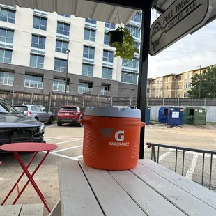 an orange cooler on a picnic table