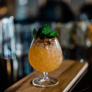 a cocktail in a glass on a cutting board