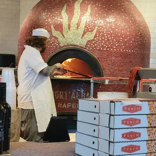 a man putting pizza into a brick oven