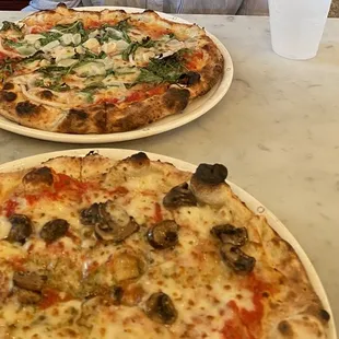Margarita pizza with garlic, onion, and arugula.   Napoli pizza with mushrooms.