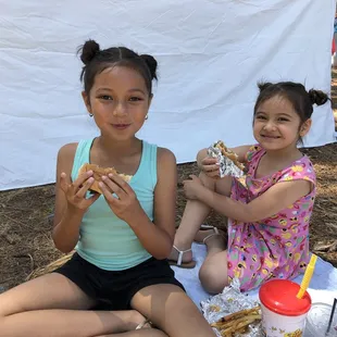 two young girls eating a sandwich