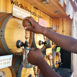 a person filling a beer from a wooden barrel