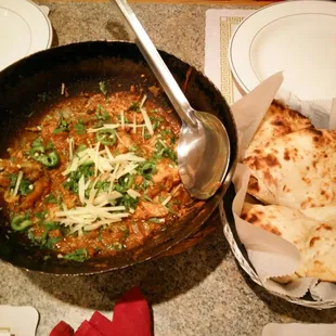 a pan of food and a plate of naan bread