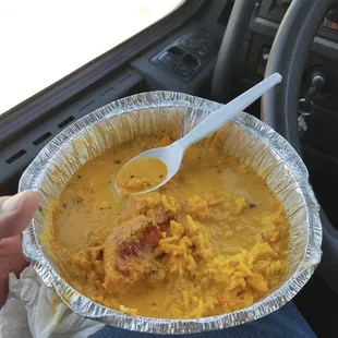 a hand holding a foil container of food