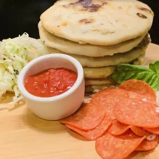 a stack of tortillas and a bowl of salsa