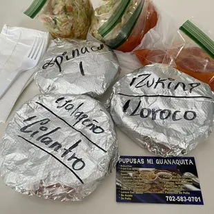 Five different pupusas with cabbage and red sauce