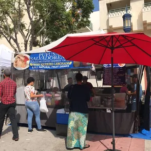 a group of people standing under a red umbrella