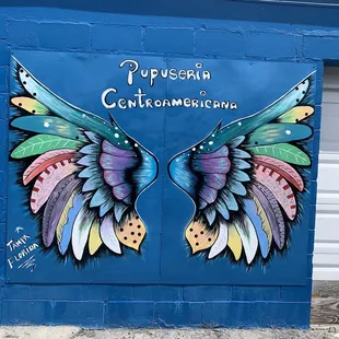 colorful wings painted on the side of a building