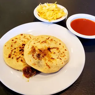 "Revueltas" and "Frijol con loroco y queso" pupusas with slaw and red salsa.