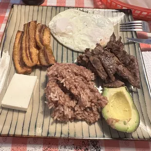 Salvadorian breakfast  Rice mixed with beans, steak, eggs, avocado, fried plantains, cheese and tortillas.