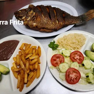 two plates of fish, rice, and vegetables