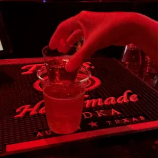 a person pouring a drink into a shot glass
