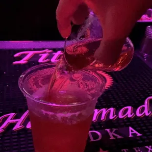 a person pouring a drink into a glass