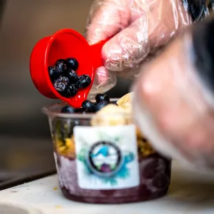 a person pouring blueberries into a cup
