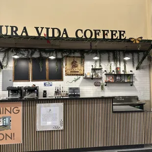 a counter with a sign that says pura vida coffee coming soon