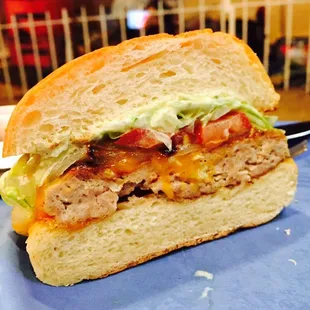 chicken burger with grilled onions, lettuce, tomato, cheddar, and yogurt sauce