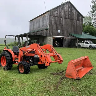 a tractor and plow in front of a barn