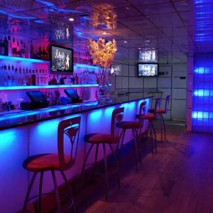 a bar with neon lights and bar stools