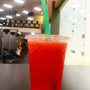 a red drink in a plastic cup with a green straw