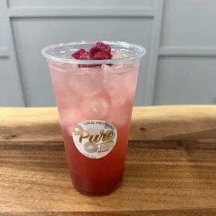 a pink drink in a plastic cup on a wooden table