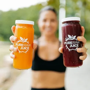 a woman holding two bottles of juice