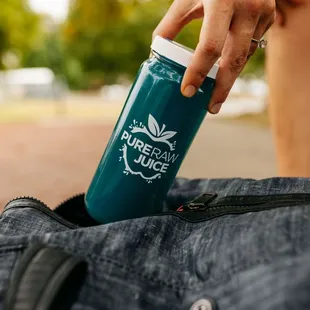 a person holding a bottle of pure raw juice