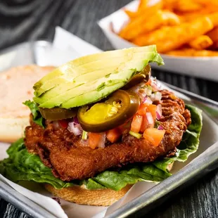 a chicken sandwich with lettuce, tomato, and avocado