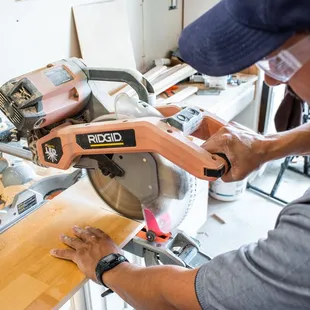 a man using a circular saw to cut a piece of wood