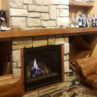 bottles of wine on shelves above a fireplace