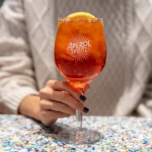 a woman holding a glass of orange juice