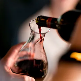 a person pouring a glass of wine